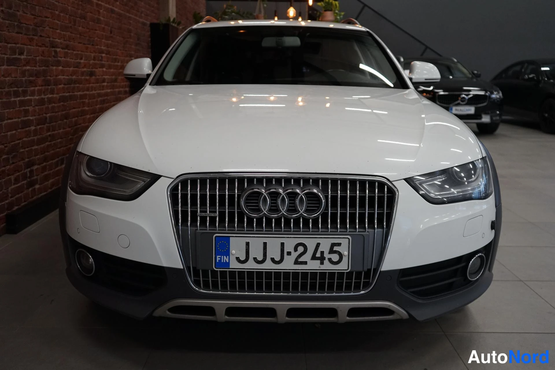 Edestä: Auton etunäkymä: valkoinen Audi, keskusritilä ja Audi-merkki, rekisterikilpi.