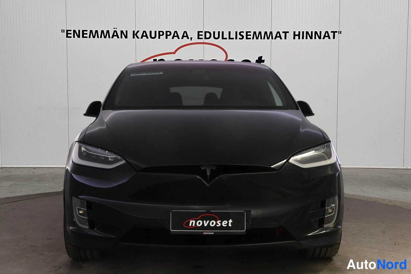 Edestä: Mustan Tesla Model X:n etunäkymä, LED-ajovalot ja Teslan logotunnuksella varustettu etusäleikkö.