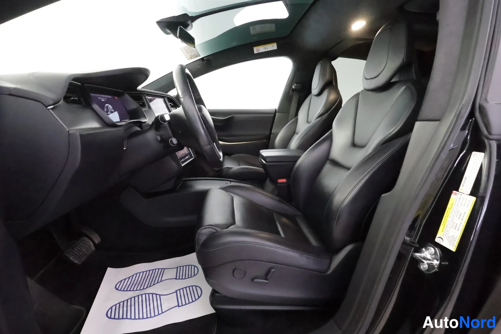 Edestä: Tesla Model X:n etummat istuimet näkyvät avoimesta etiovesta.