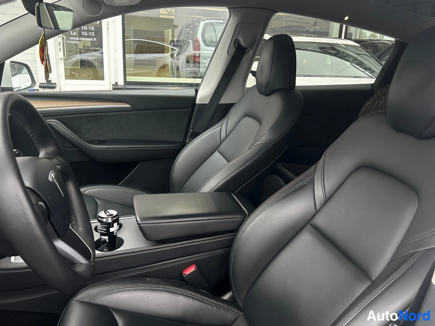 Muu: Mustat nahkaistuimet ja keskikonsoli Tesla Model Y:n ohjaamosta sivulta kuvattuna.