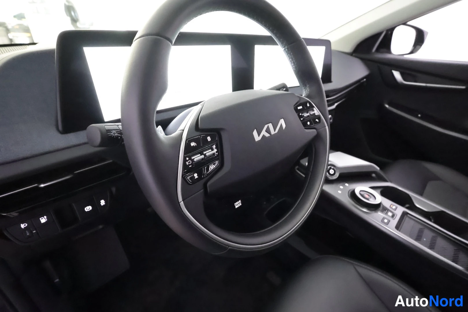Sivulta: Auton sisätilat: Kia-merkkinen ohjauspyörä, infotainment-näytöt ja keskikonsolin kahva-avoid vaihdin.