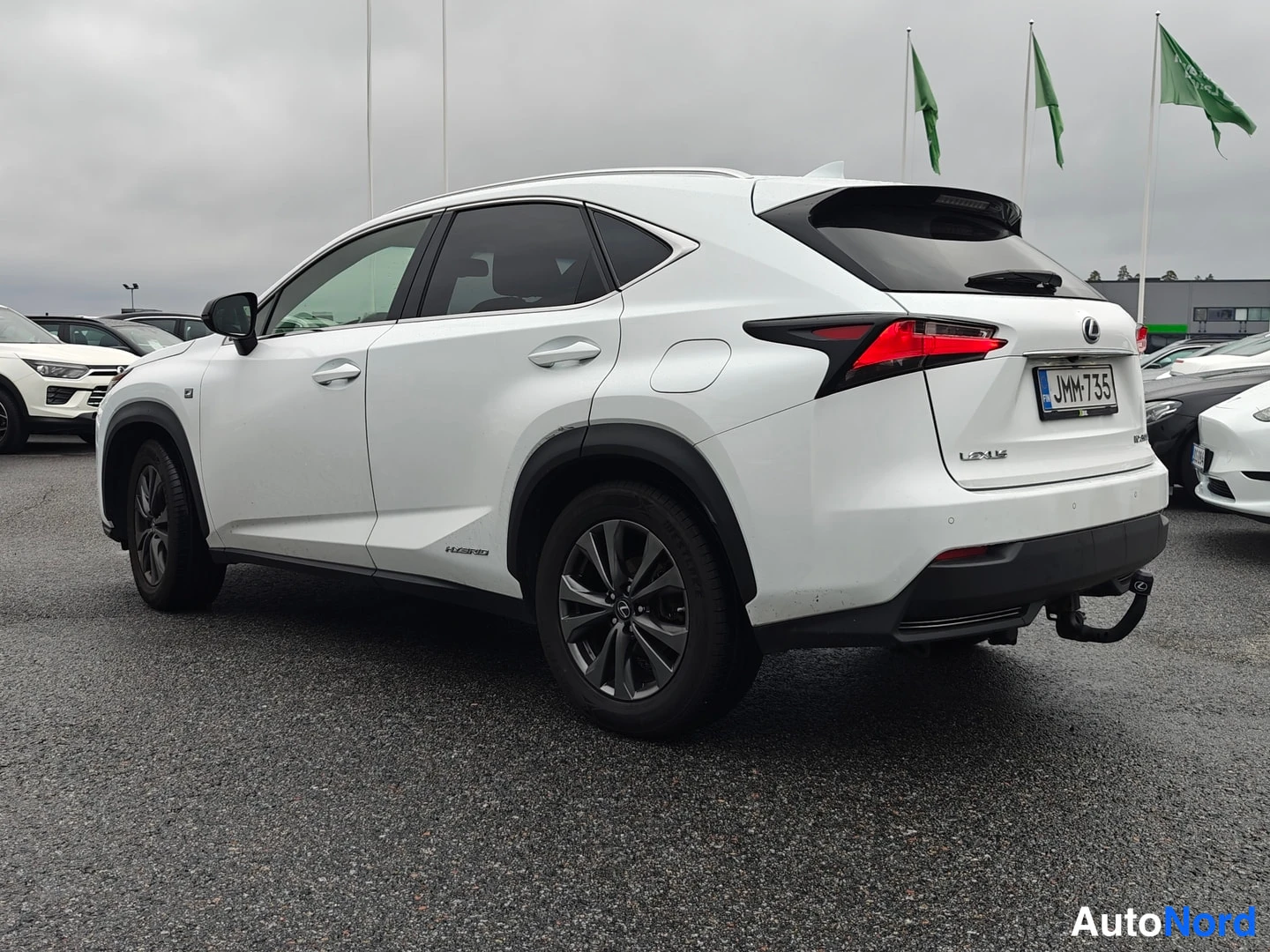 Takaviisto: Valkoisen Lexus NX -maasturin takaviisto vasemmalta; takavalot, rekisteritunnus ja perävaikkukoukku näkyvät.