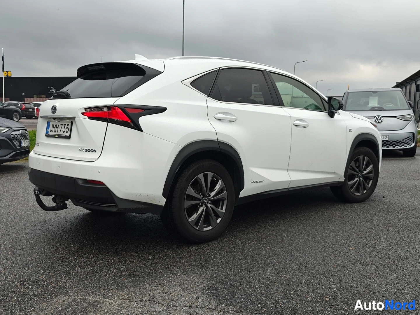 Takaviisto: Valkoisen Lexus NX 300h:n takaviisto vasemmalta; takavalot, rekisteritunnus ja perävaikkukoukku näkyvät, auto seisoo parkkipaikalla.