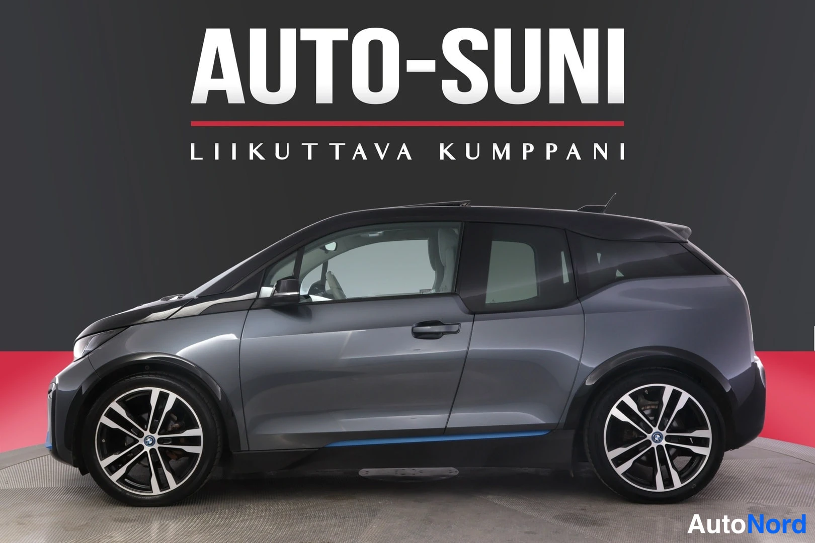 Sivulta: Auton sivukuva: tummanharmaa BMW i3, musta katto ja lavastus