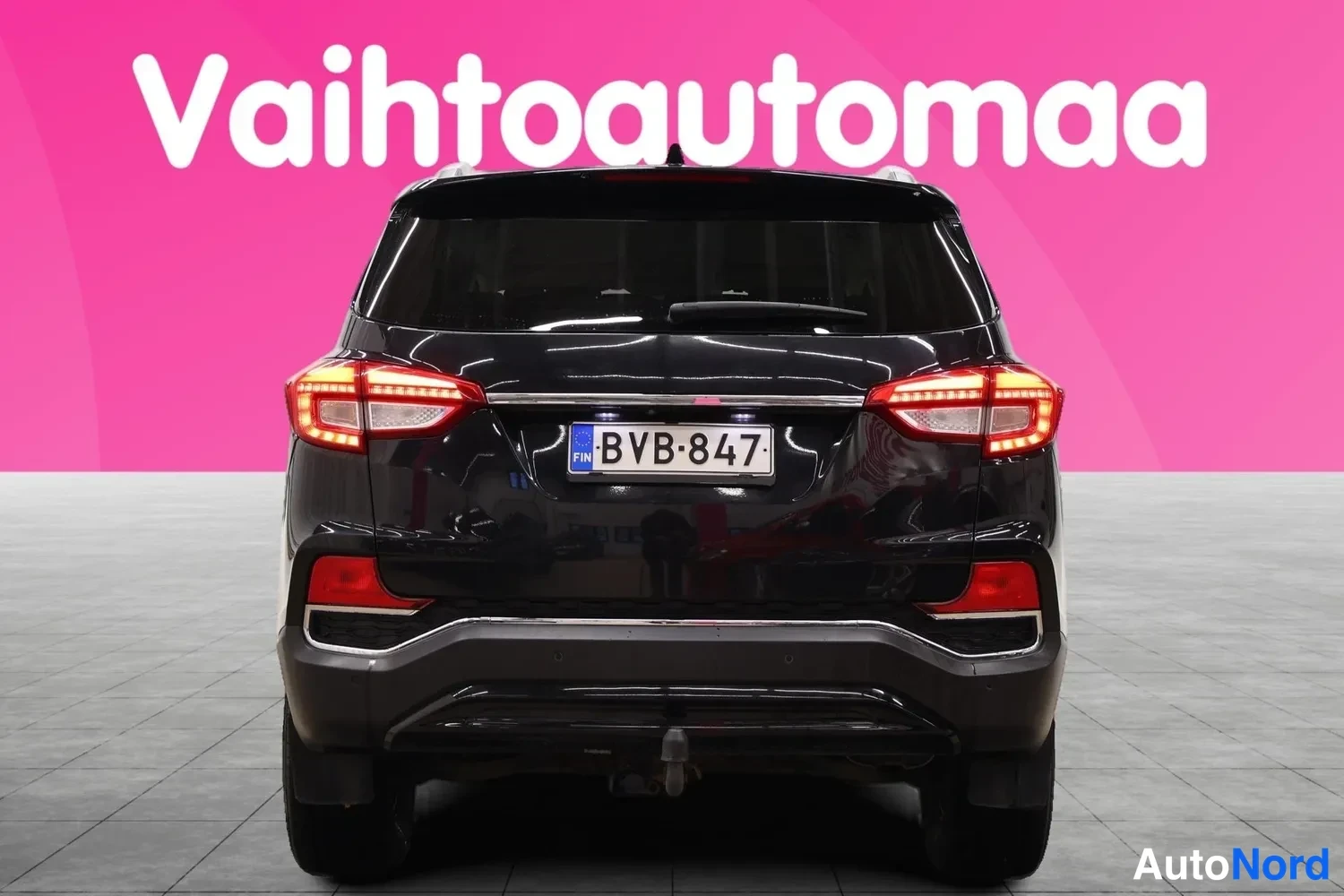 Takaa: Mustan henkilöauton takaosa, rekisterikilpi, savukeheinä...
