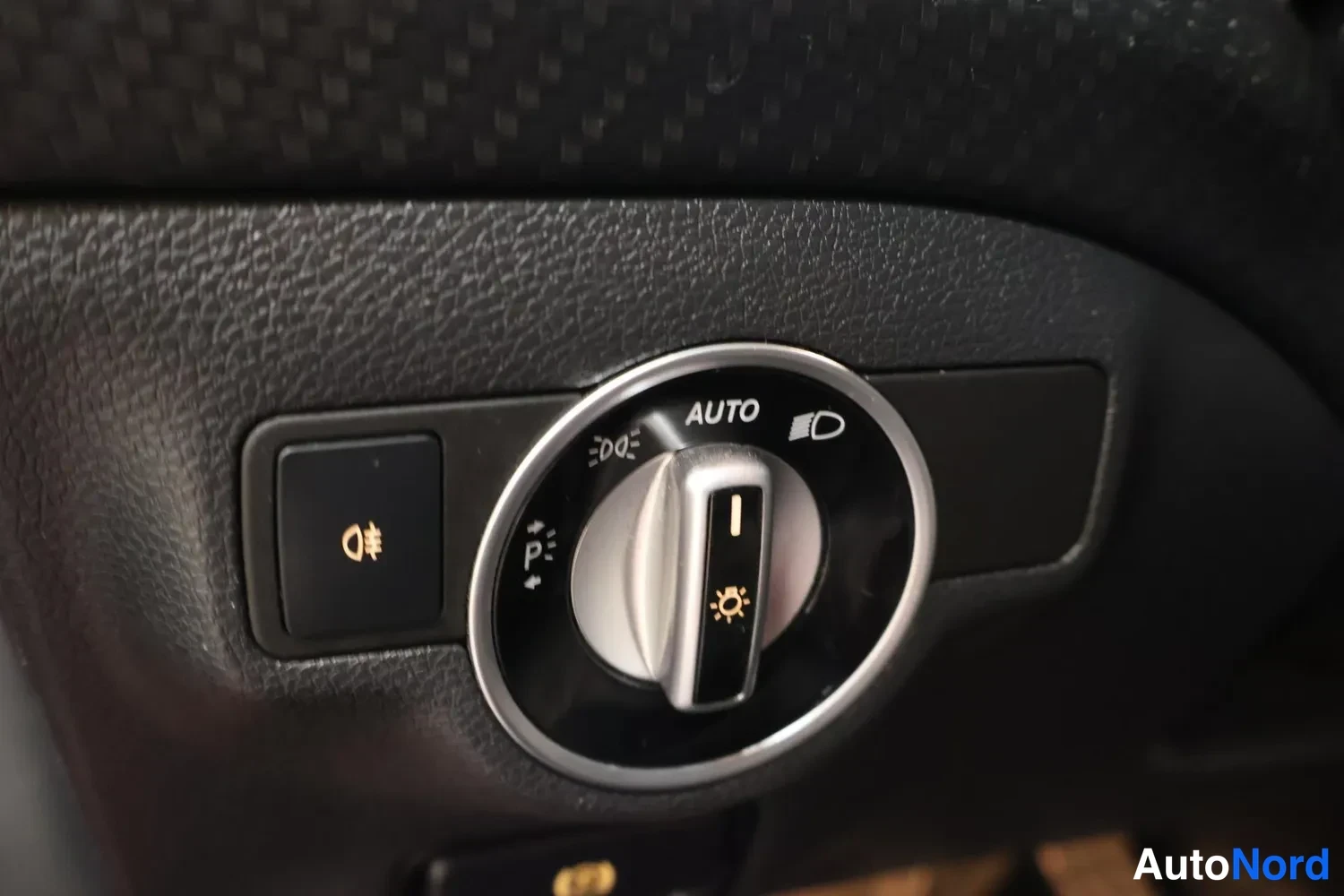 Muu: Lähikuva valaistuksen säätökäyttäjästä AUTO-asennossa, jossa symbolit autopilot valoille, sumuvaloille ja pysäköintiä varten.