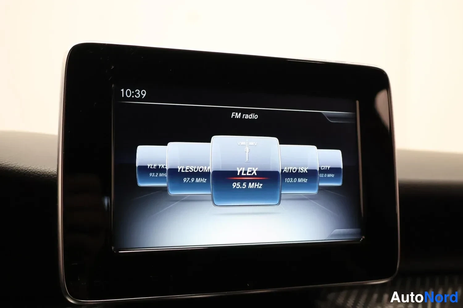 Muu: Tallennettu sisäkuva: kojelaudan näyttö näyttää FM-radiovalikon, valittuna kanava YLEX 95.5 MHz, kello 10:39.
