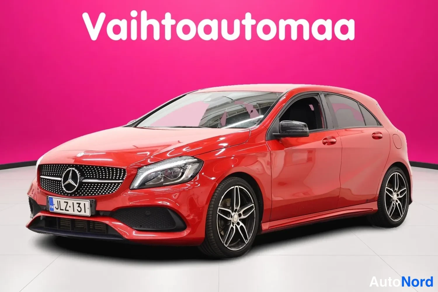 Etuviisto, nokka vasemmalle: Punainen Mercedes-Benz A -mallinen henkilöauto vinosti edestä vasemmalta kuvattuna, rekisteritunnus.