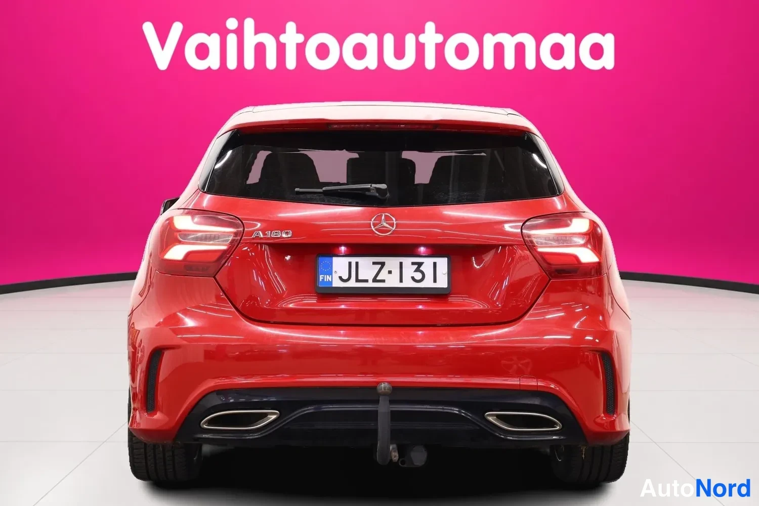 Takaa: Punaisen Mercedes-Benz A 180:n takaapäin otettu kuva, rekisterikilpi ja kaksiosaiset pakoputkien suuttimet näkyvät.