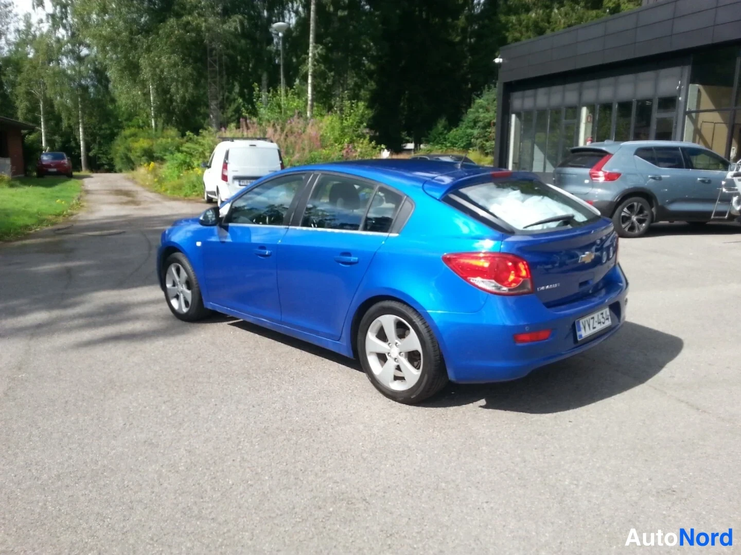 Takaviisto: Chevrolet Cruze -viistoperän takakolmasosanäkymä vasempaan nokkaan; sinisen auton sivut, takavalot ja rekisterikilpi näkyvät.