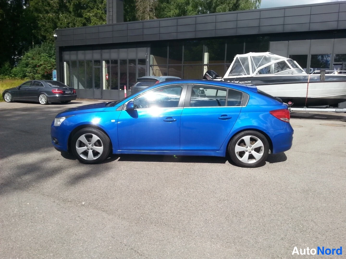 Etuviisto, nokka vasemmalle: Chevrolet Cruze -viistoperän sivunäkymä; auton etupää ja vasen kylki näkyvät rinnakkain, väri on sininen.