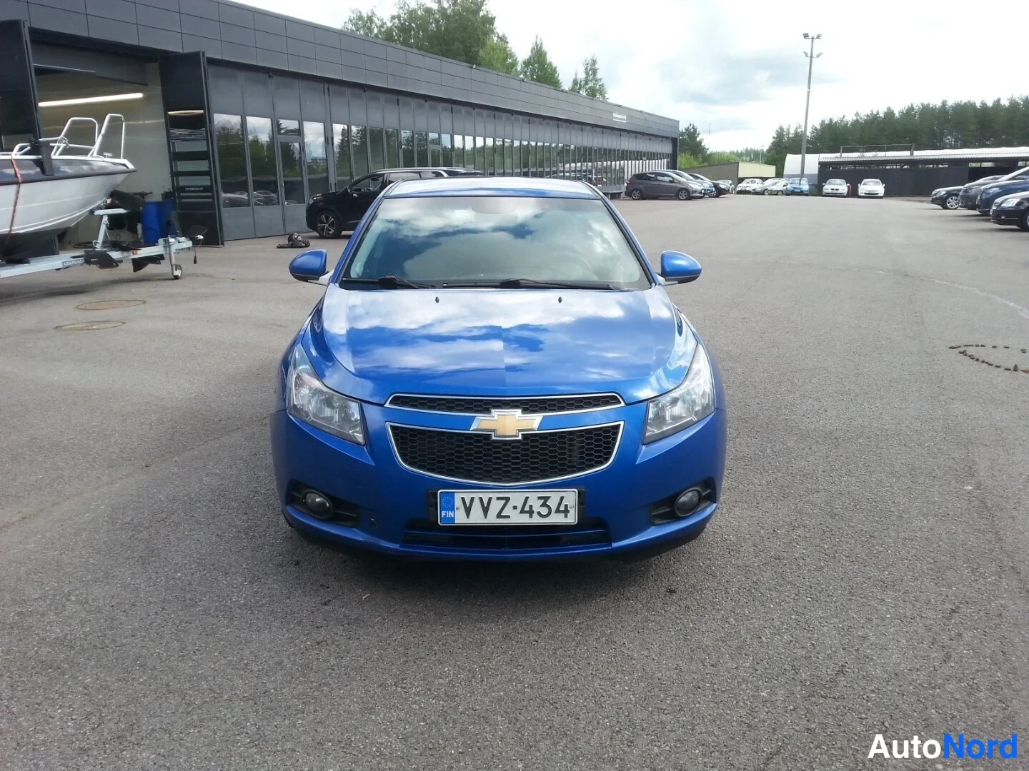Edestä: Sininen Chevrolet Cruze edestä päin kuvattuna pysäköintialueella, rekisterikilpi.