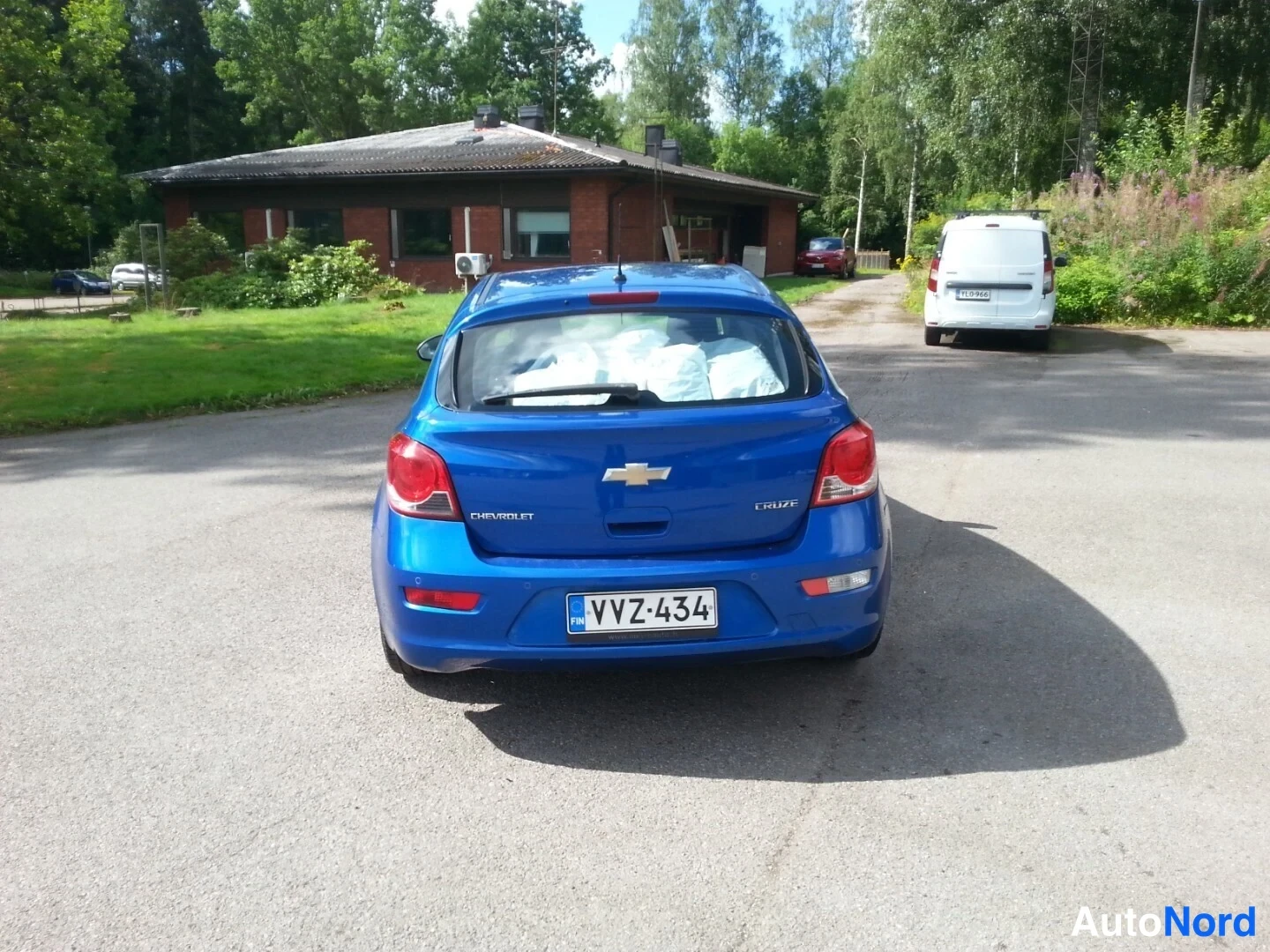 Takaa: Sinisenä harkkorväriä olevan Chevrolet Cruze -viistoperän takanäkymä; rekisterikilpi, Chevrolet-logo ja Cruze-merkintä takaluukussa.