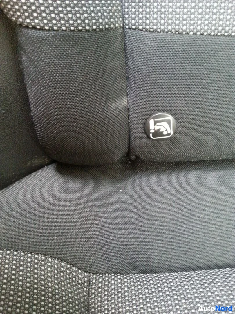 Muu: Tarkakuva tummasta kangasistuimesta, jossa on tekstiilityyppi ja ISOFIX-merkintä istuimen sivussa.