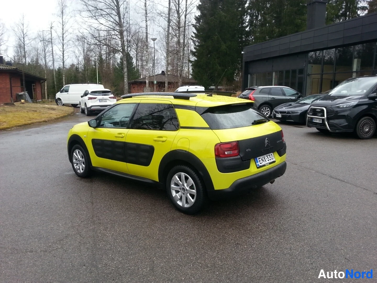 Takaviisto: Keltainen Citroën C4 Cactus -henkilöauto takakulmasta kuvattuna pihamaalla.