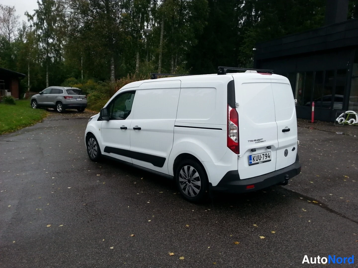 Takaviisto: Valkoinen Ford Transit Connect -pakettiauto takaa ja oikealta sivulta, kattoteline ja rekisterikilpi näkyvissä.