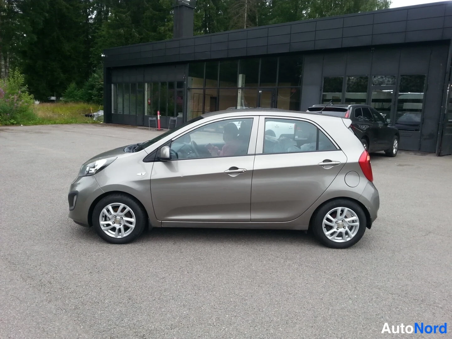 Sivulta: Kia Picanto -henkilöauton vasen kylki sivulta nähtynä talon edustalla.