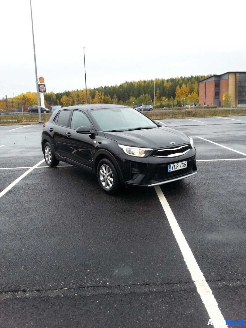 Etuviisto, nokka oikealle: Kia Stonic mustana kolmesta neljäsosasta edessä oikealta, rekisterikilpi, sadekärrypihalla.