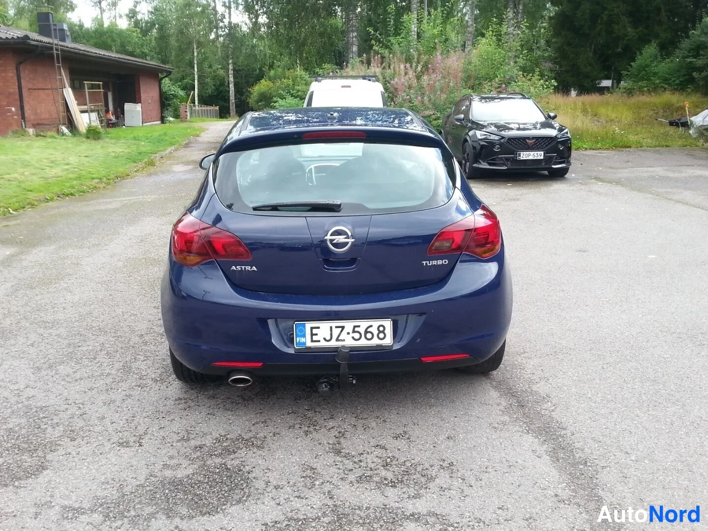 Takaa: Auto takaa, tummansininen, takaluukussa Astra ja Turbo -merkit, rekisteritunnus, vetokoukku ja yksi pakoputki näkyvissä.