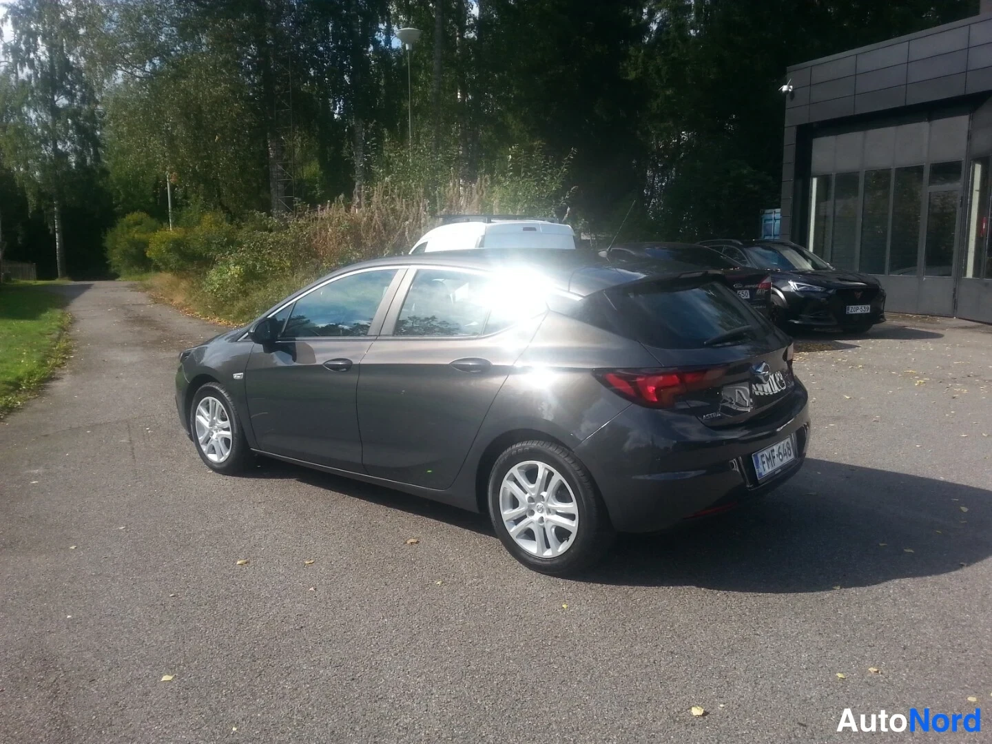 Takaviisto: Tummanharmaa hatchback takakolmanneltakulmasta perää oikealle kääntyneenä, rekisteritunnus, auringonheijastus takakannesssa.