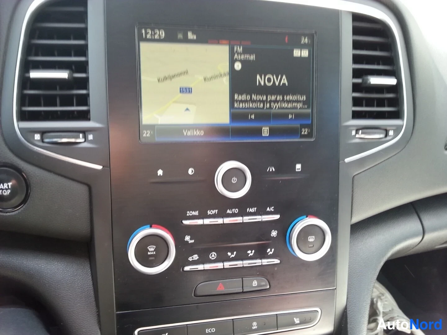 Yksityiskohta: Keskikonsolin infotainmenäyttö kartta- ja radionäkymässä (Radio Nova), alla kaksialueinen automaattinen ilmastointi ja ECO-valinta.