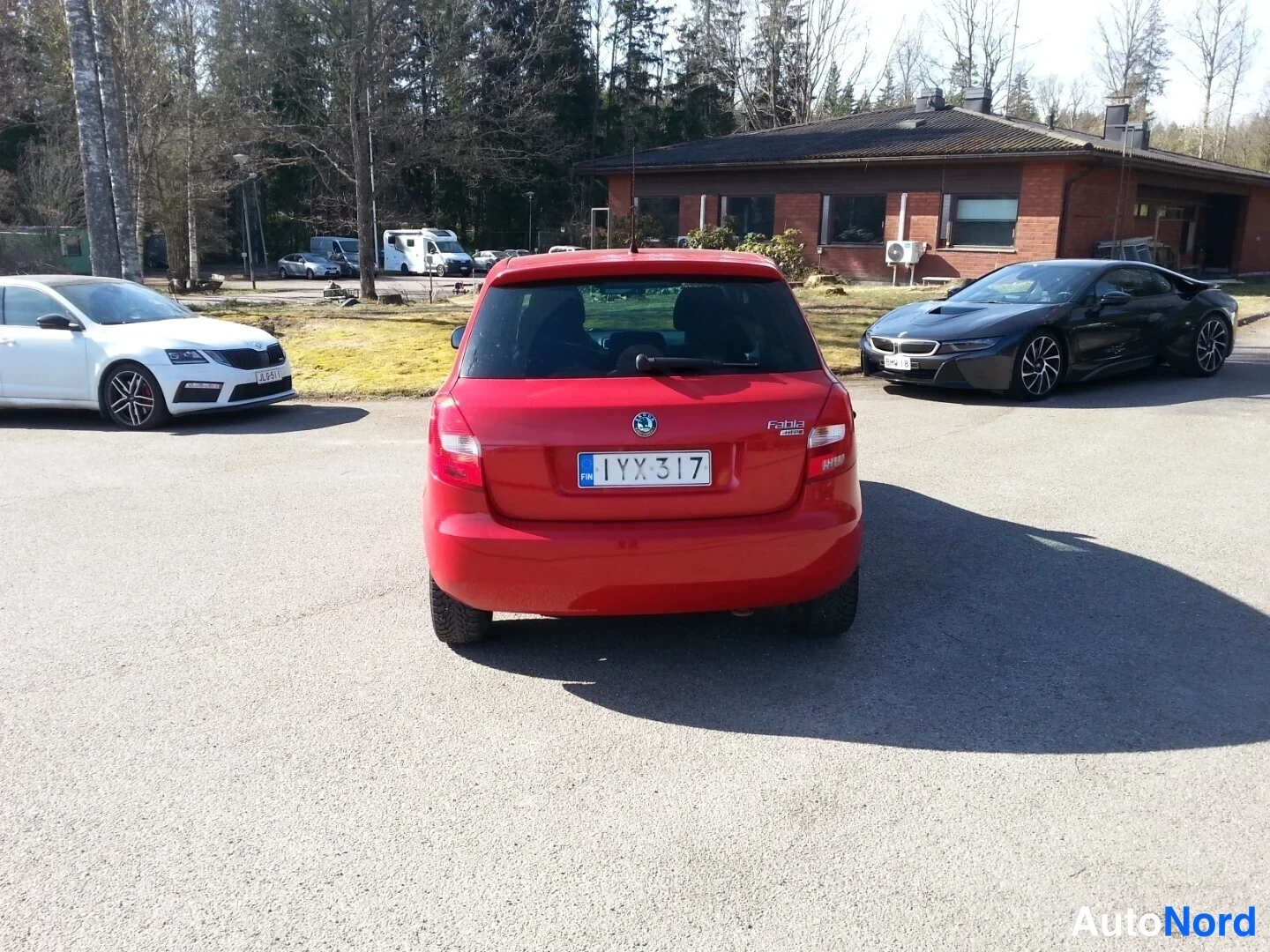 Takaa: Punainen henkilöauto takaa kuvattuna parkkipaikalla, rekisteritunnus, perällä Fabia-merkintä.