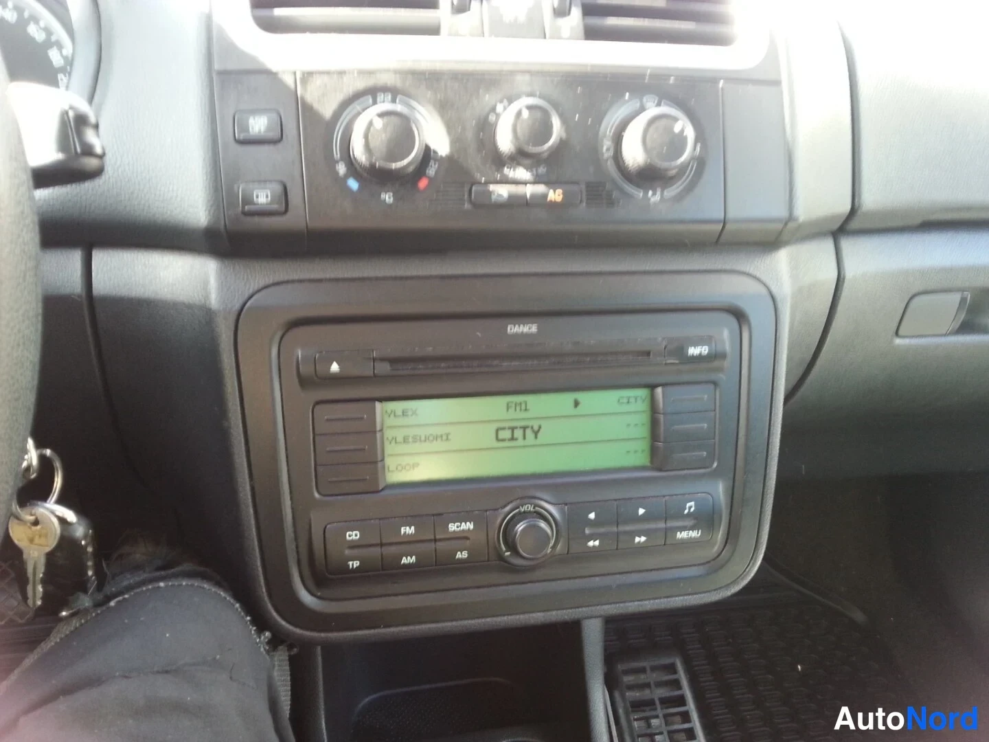 Muu: Kojelauta: kolme säätöpyörää, A/C-merkintä ja radio (Dance) näytöllä CITY, avaimet lukossa.