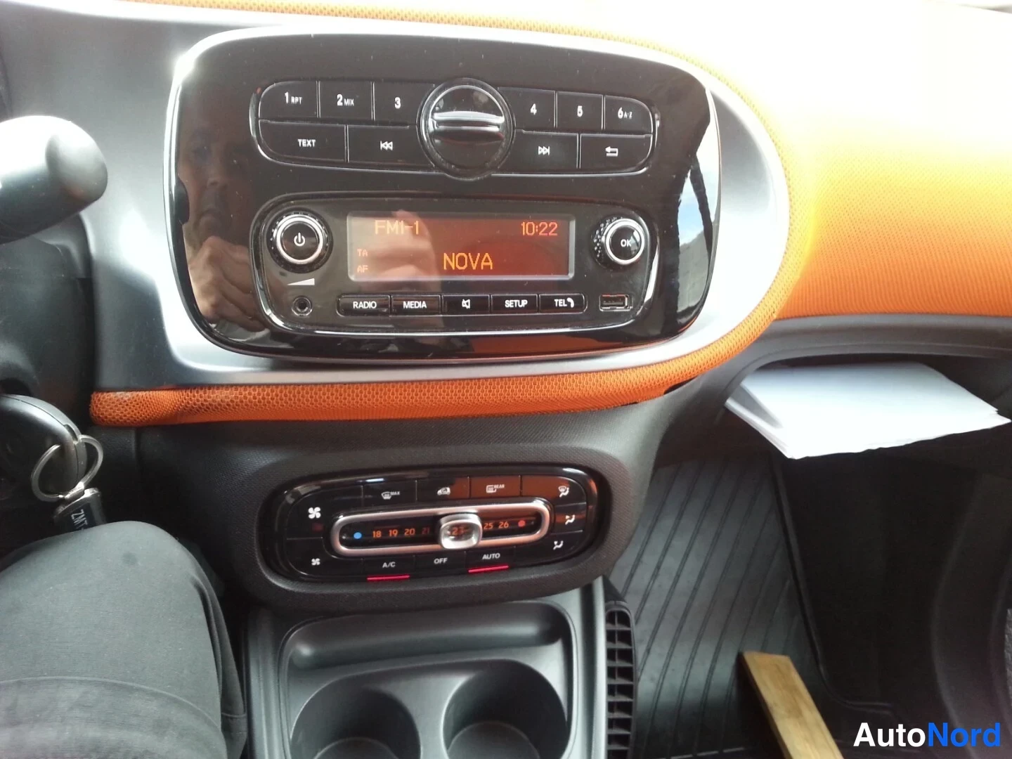 Muu: Kojelauta: radio näyttää FM=1, NOVA, kello 10:22; alla automaattinen ilmastointi (OFF ja AUTO, A/C) ja kupiteline.