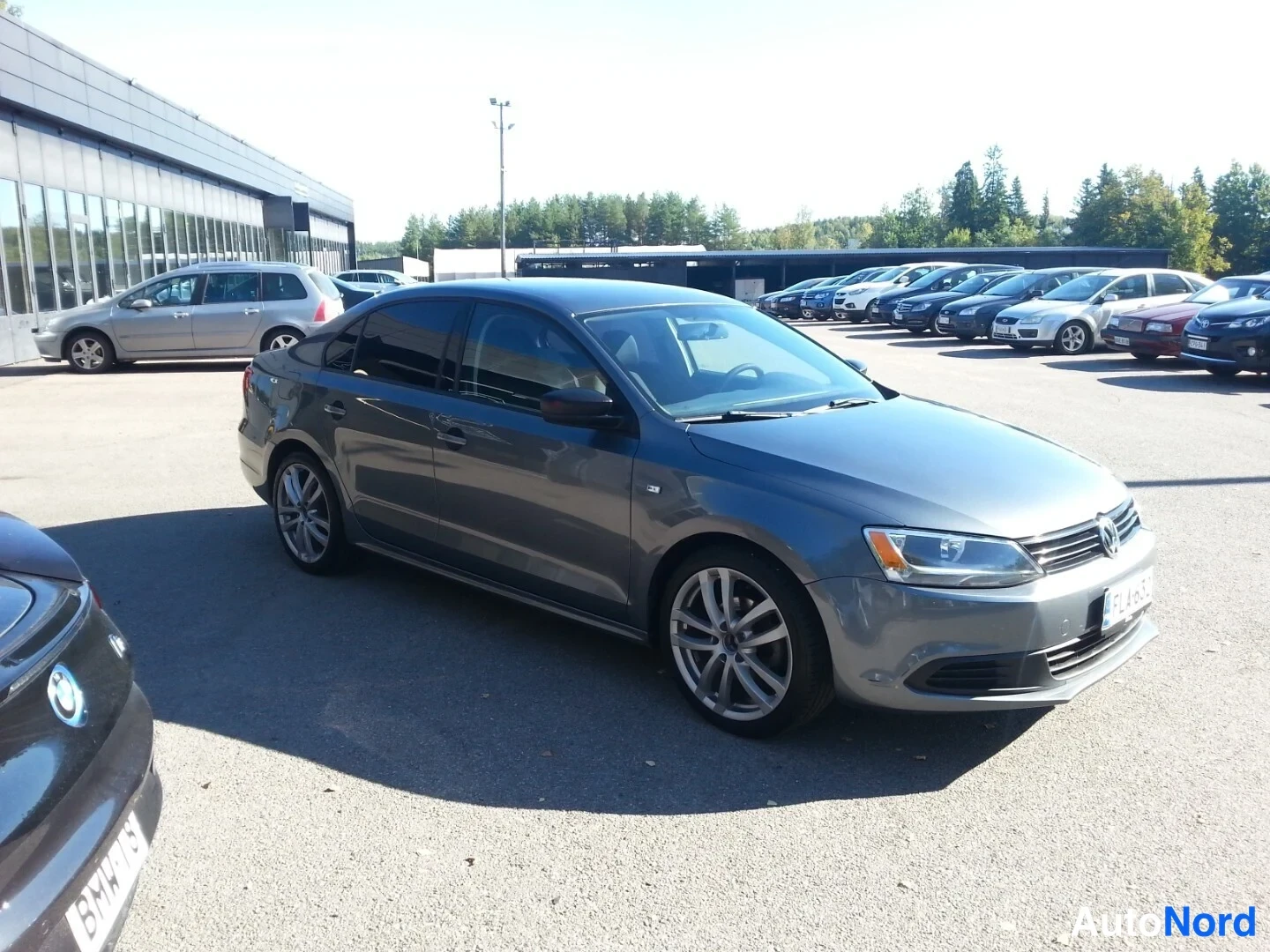 Etuviisto, nokka oikealle: Volkswagen Jetta -sedanin etukulmanäkyminen metallinhohtoharmaana parkkipaikalla; etusäleikkö ja ajovalot näkyvät.