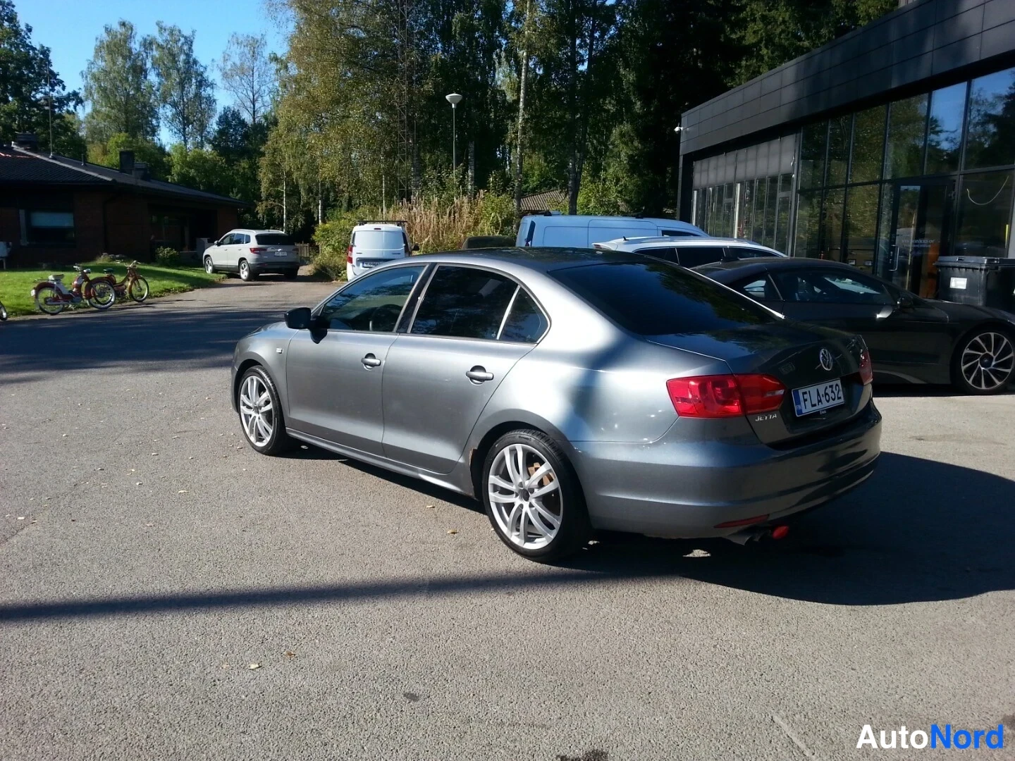 Takaviisto: Volkswagen Jetta -sedanin takakulma metallinhohtoharmaana; takavalot ja rekisterikilpi näkyvät.