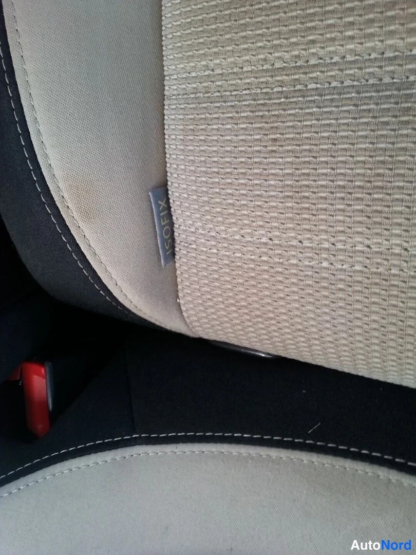 Muu: Sisäkuva: vaalean kangasverhoillun istuimen sivussa lukeva ISOFIX-tekstiililappu.