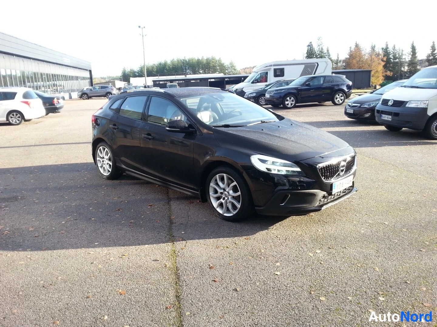 Etuviisto, nokka oikealle: Musta Viistosti edestä oikealta valokattettu Volvo V40, etusäleikkö ja konepelti näkyvät, kattokaiteet katolla.