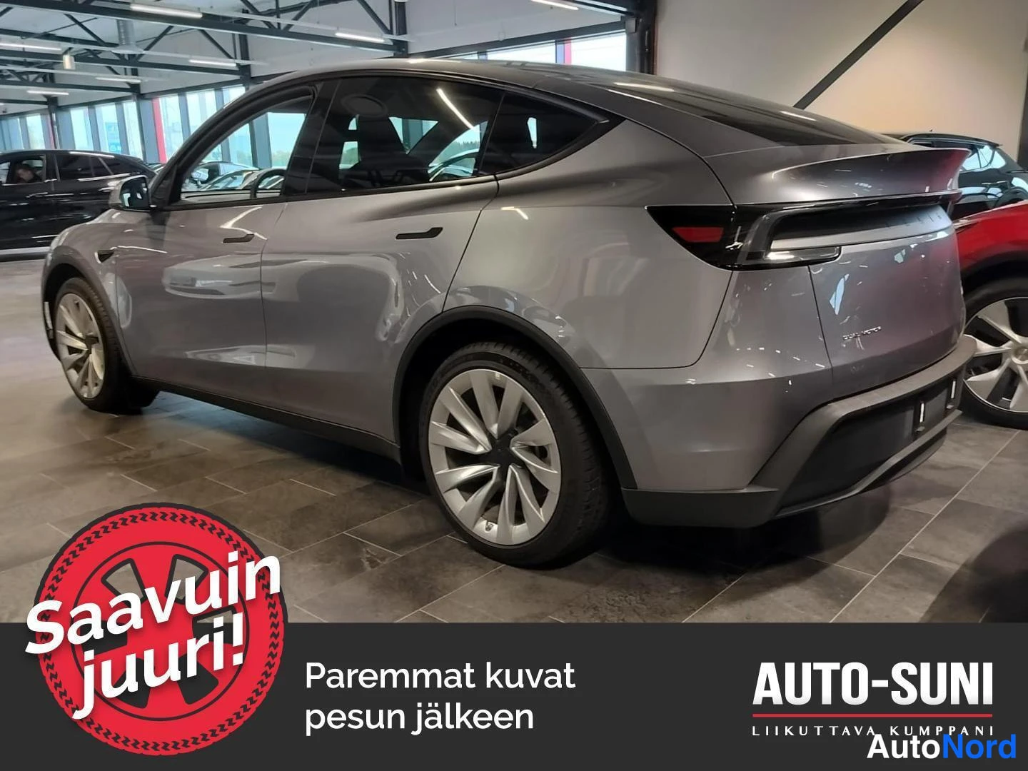 Takaviisto: Hopeanharmaa Tesla Model Y takaloksu vasemmalta kuvattuna näyttelytilassa.