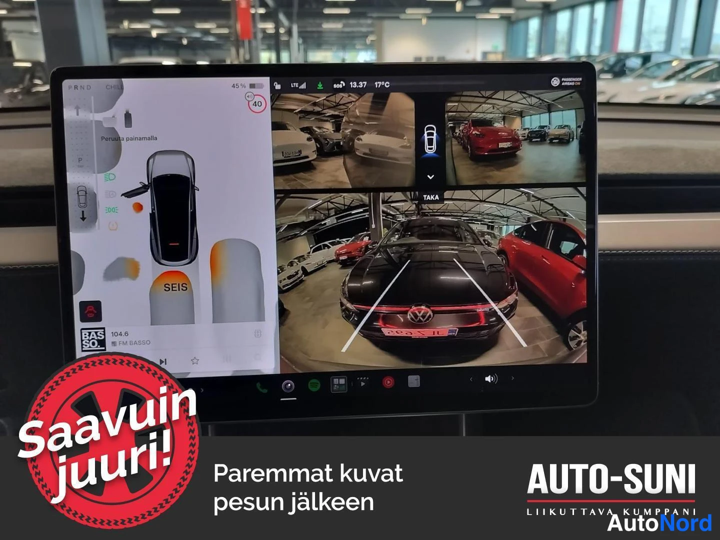 Muu: Auton kesk näytöllä peruutuskamera ja ympärivaranäkymä; ruudussa näkyy tumma Volkswagen ja pysäköintihallin muut autot.