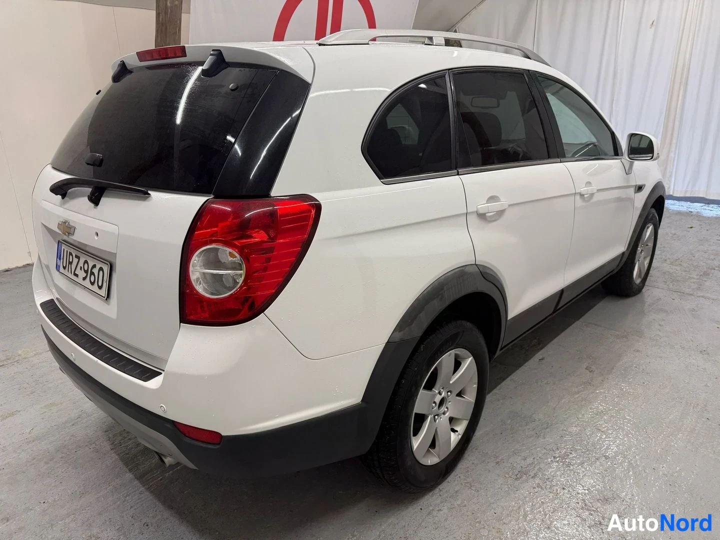 Takaviisto: Auton takakulma: valkoinen SUV, rekisteritunnus, näkyvät takavalot, takaluukku ja sivuiva.
