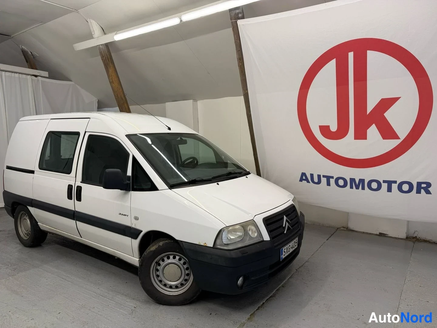 Etuviisto, nokka oikealle: Valkoinen Citroën Jumpy -pakettiauto kolmannelta kulmalta, keula ja sivu näkyvät.
