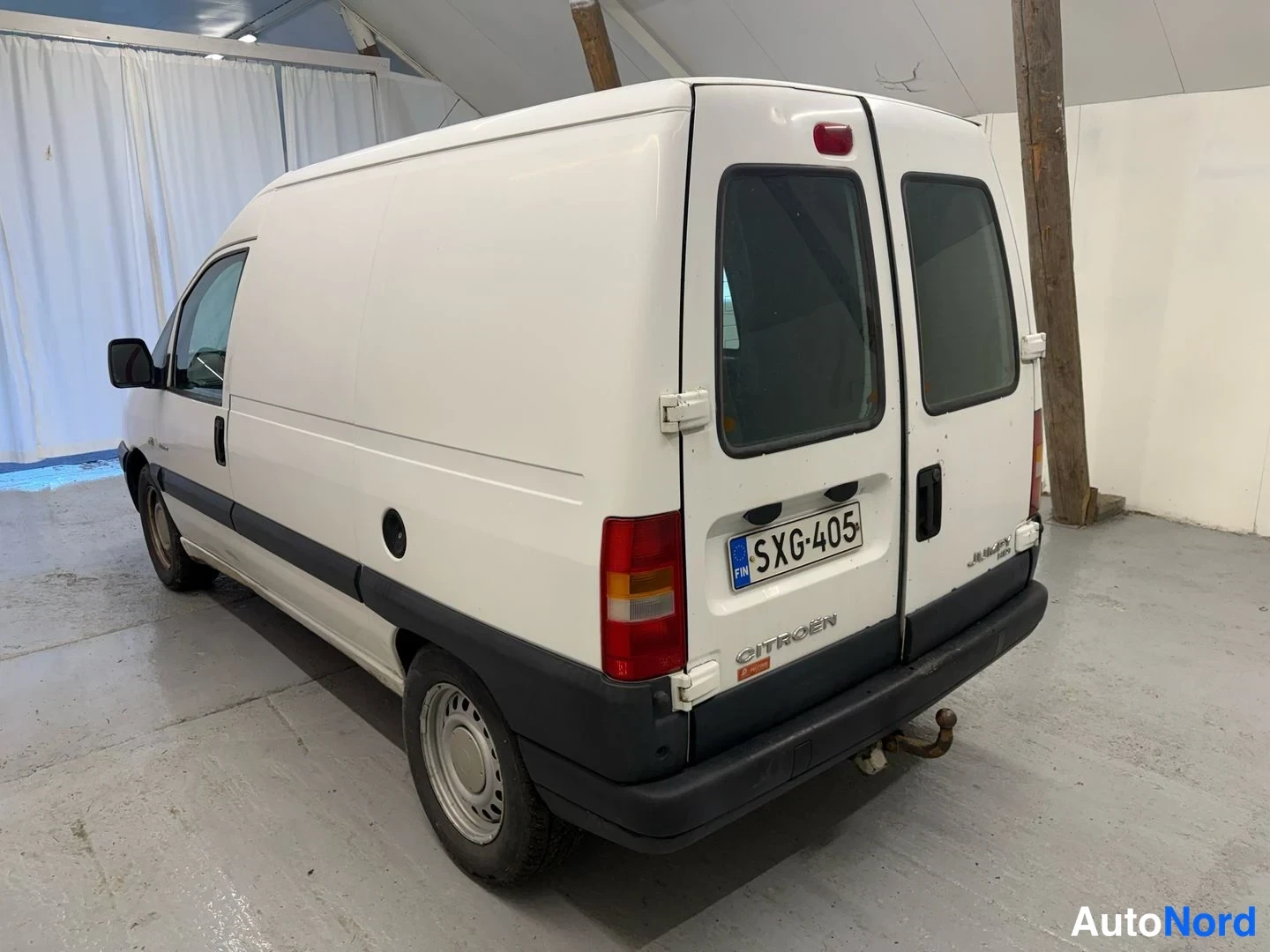 Takaviisto: Pakettiauto takaa sivusuunnasta: valkoinen Citroën Jumpy, tummat ovenkahvat ja takaikkunat.