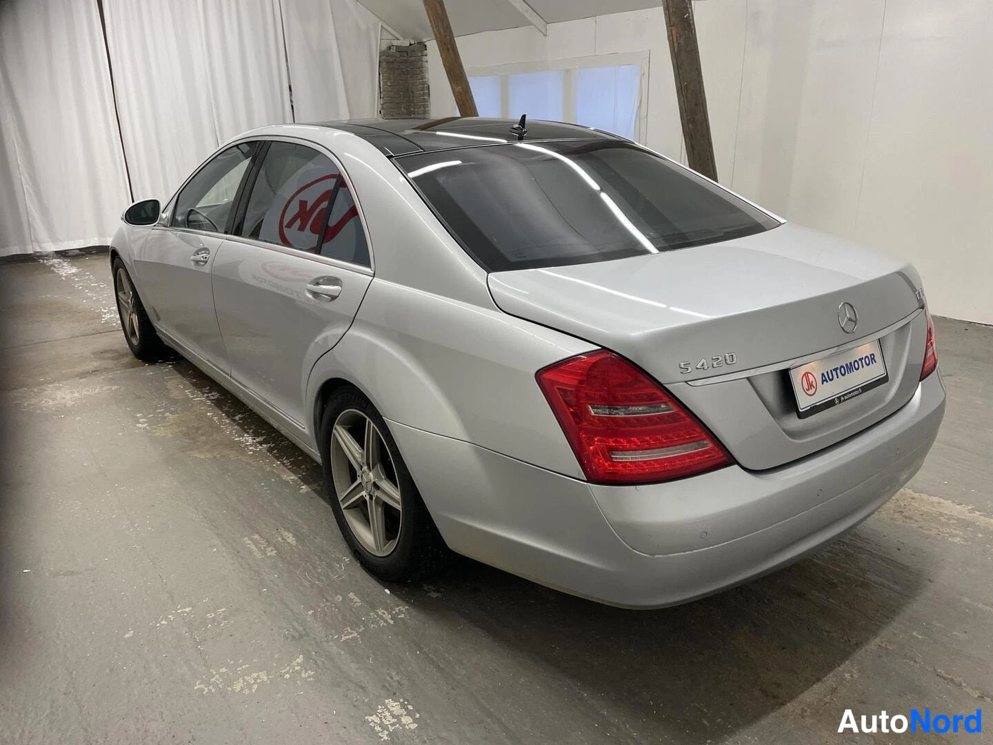 Takaviisto: Hopeanharmaa Mercedes-Benz S-sarjan sedan takaviistosta vasemmalta kuvattuna; takavalot, merkinnät 'S 420' ja vasemman puolen ovet ja pyörät näkyvät.