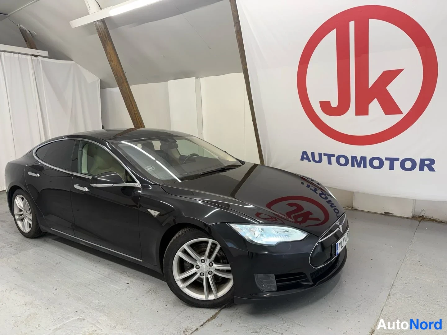 Etuviisto, nokka oikealle: Mustan Tesla Model S -sedanin etukulma vasemmalta sivulta, keulan ollessa kuvassa oikealla.