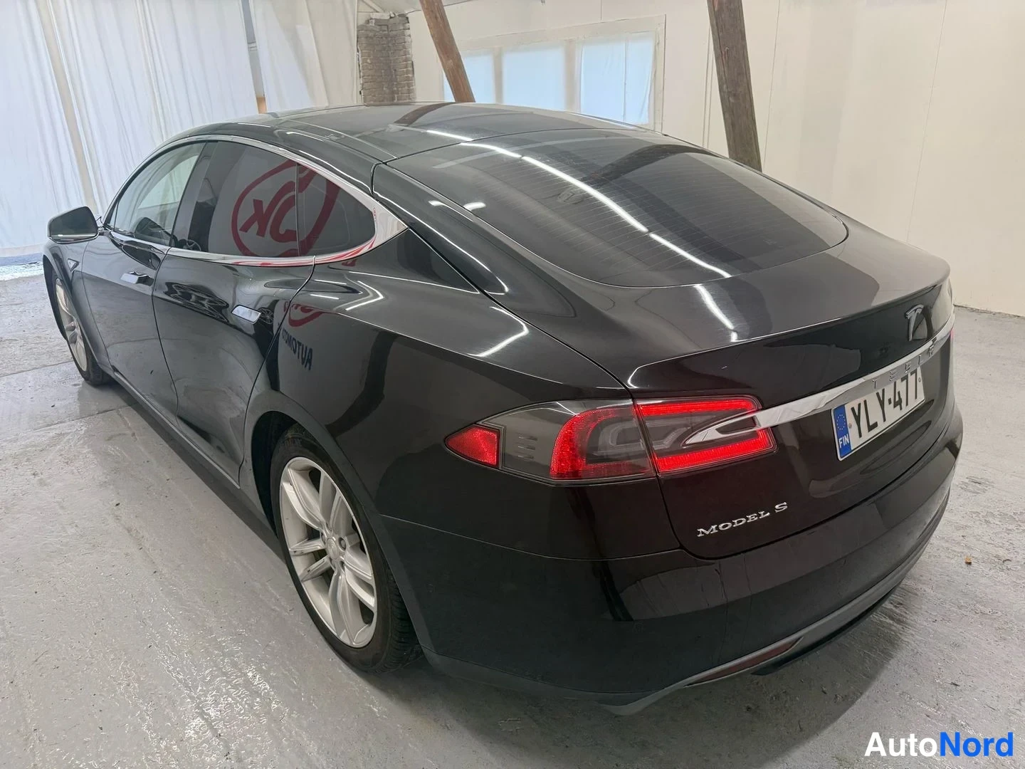 Takaviisto: Musta Tesla Model S takaa ja vasemmalta sivulta kuvattuna, rekisterikilpi ja takapuolella lukee MODEL S.