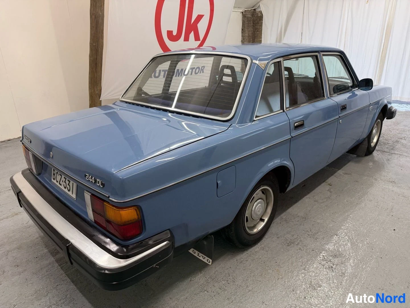Takaviisto: Sininen Volvo 244 DL takaviistosta vasemmalta kuvattuna, rekisteritunnus.