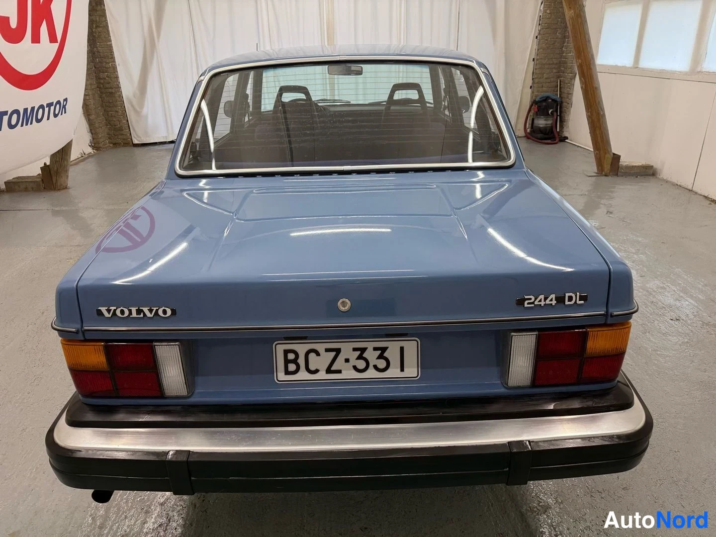 Takaa: Sininen Volvo 244 DL suoraan takaa kuvattuna, rekisteritunnus.
