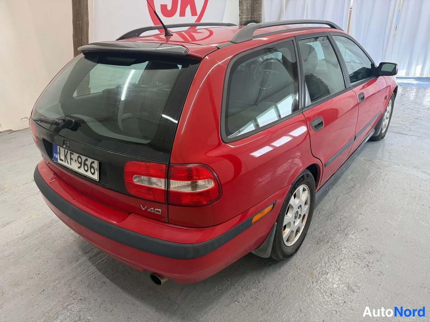 Takaviisto: Punaisen Volvo V40 -farmarin takakulmanäkyväs: takavalot, -rekisterikilpi ja kattokaiteet näkyvät.