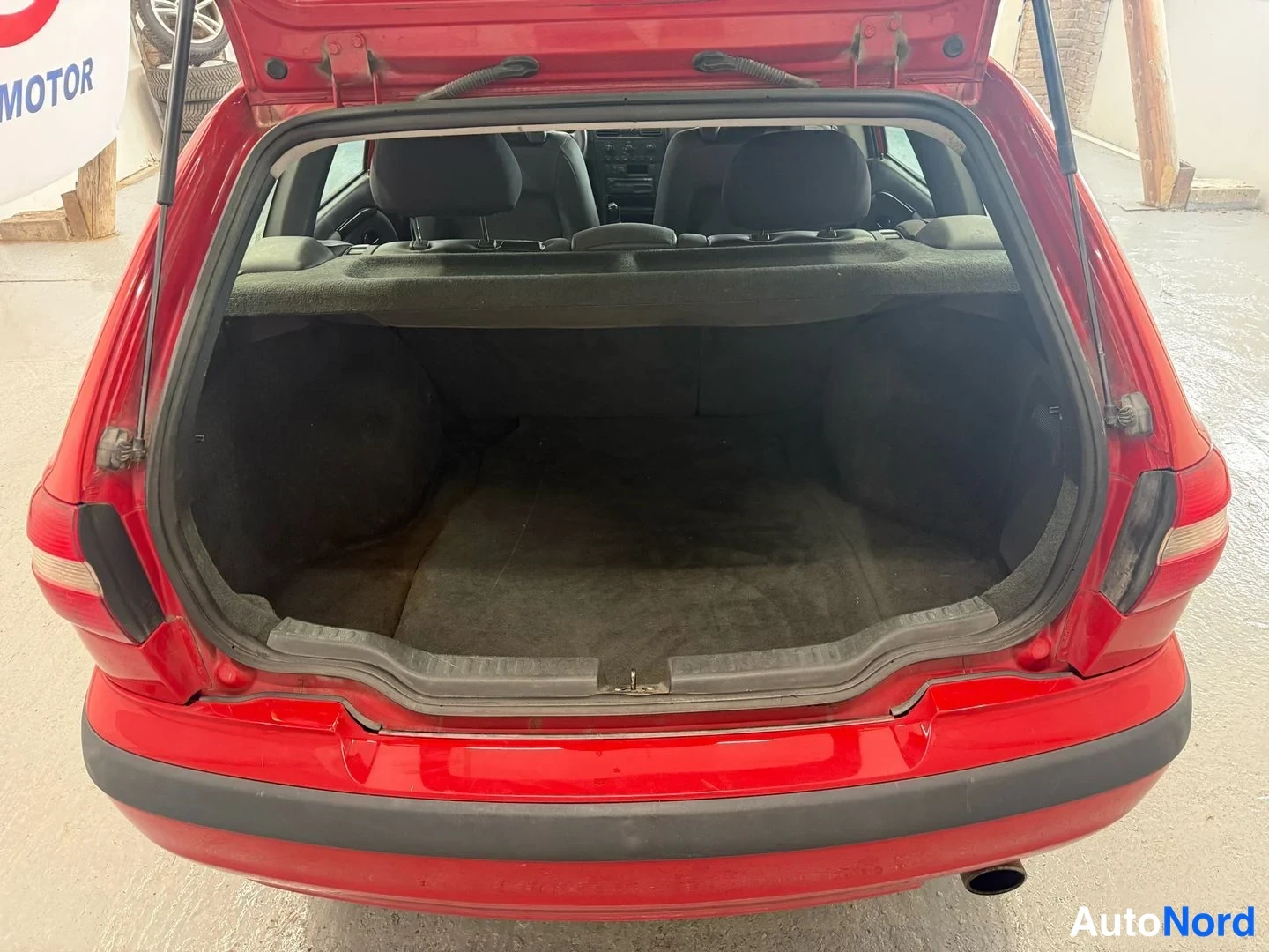 Takaa: Punaisen Volvo V40 -farmarin avoin tavaratila; takaluukku on ylhäällä ja tavaratilan matto näkyy.