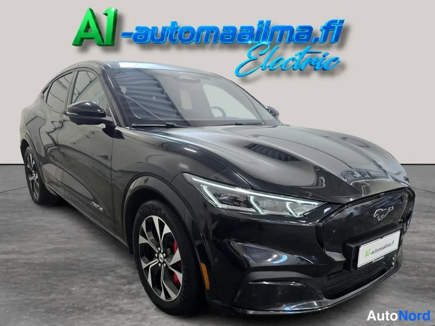 Etuviisto, nokka oikealle: Musta Ford Mustang Mach-E etuosa kolmannelta oikealta, LED-ajovalot ja mustat kevytmetallivanteet näkyvissä.
