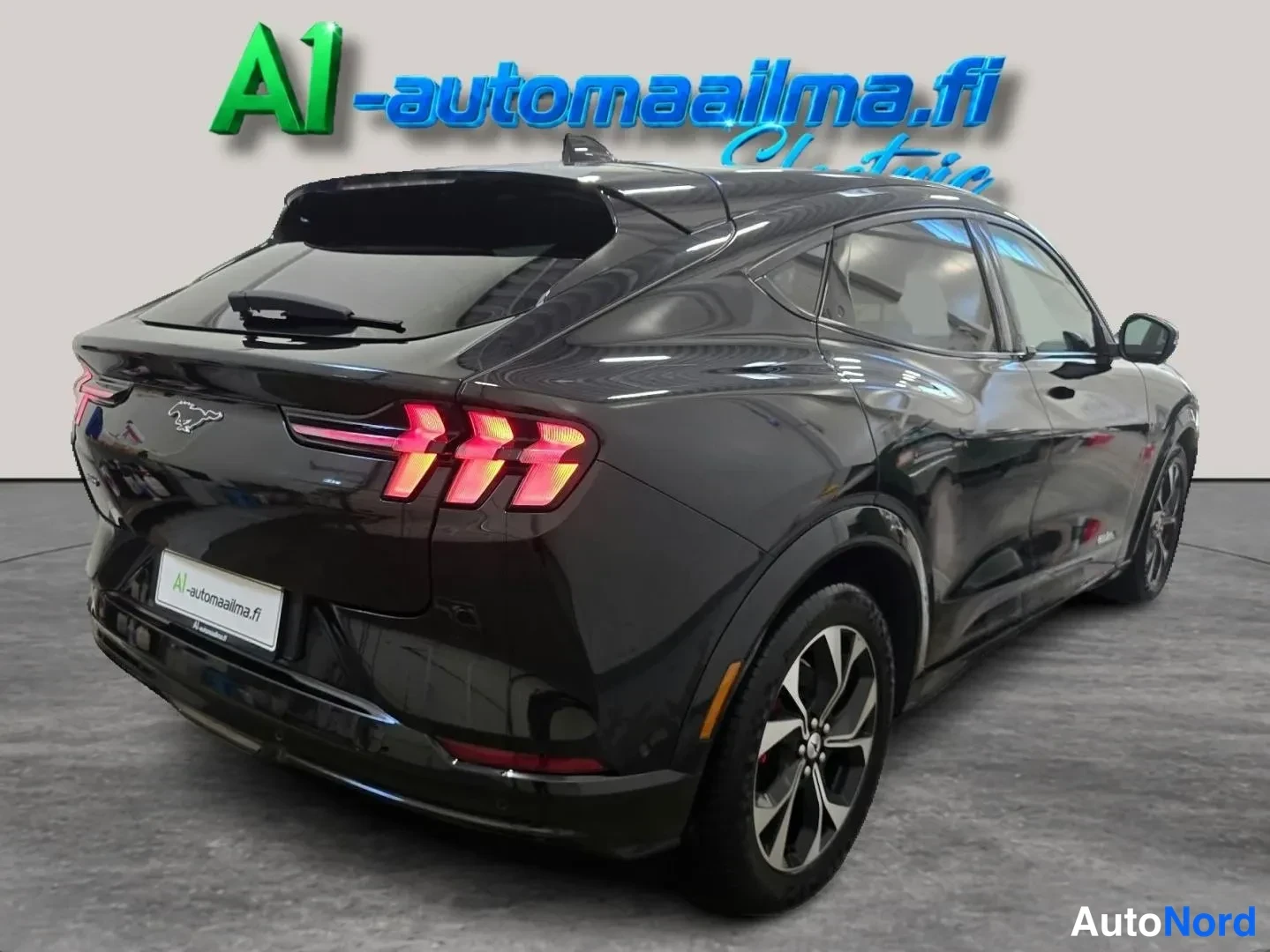 Takaviisto: Musta Ford Mustang Mach-E takaosa kolmannelta oikealta, takavalot ja pyyhinläpi näkyvissä.