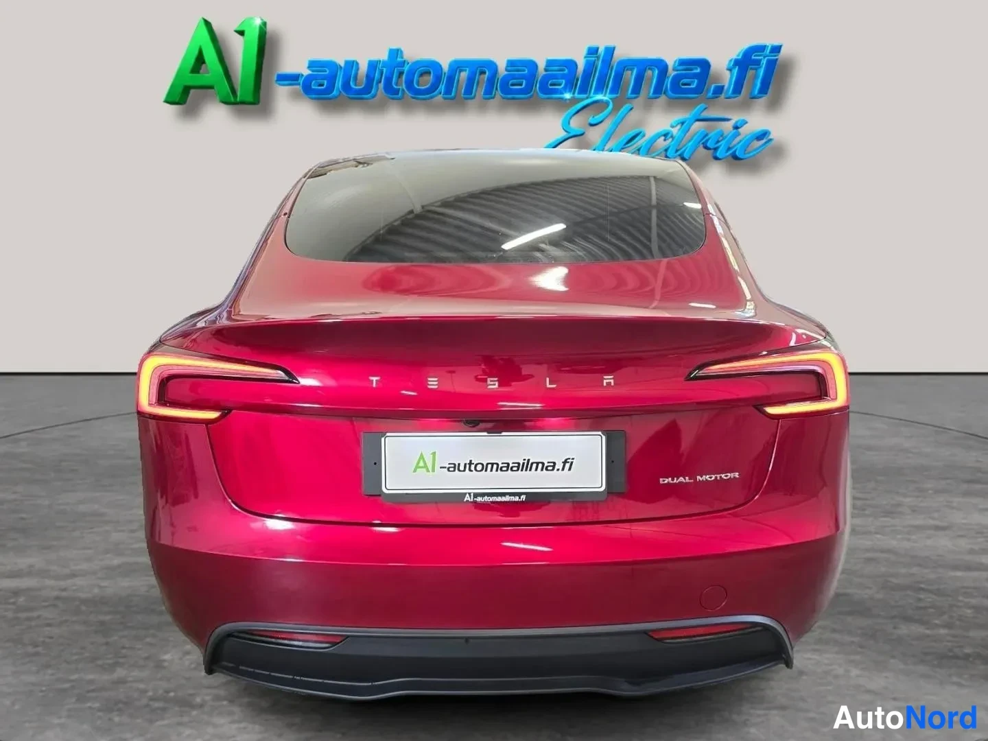 Takaa: Punaisen teslan takaosa suoraan takaa, takavalot ja DUAL MOTOR-teksti näkyvät.