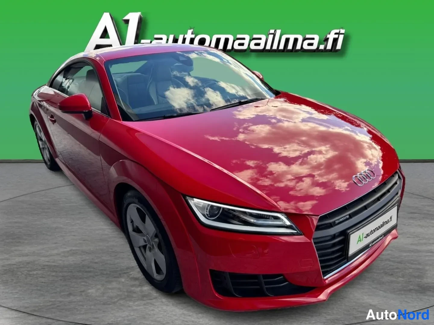 Etuviisto, nokka oikealle: Punainen Audi TT Coupé etukulmasta oikealta, etusäleikkö ja ajovalot näkyvät.