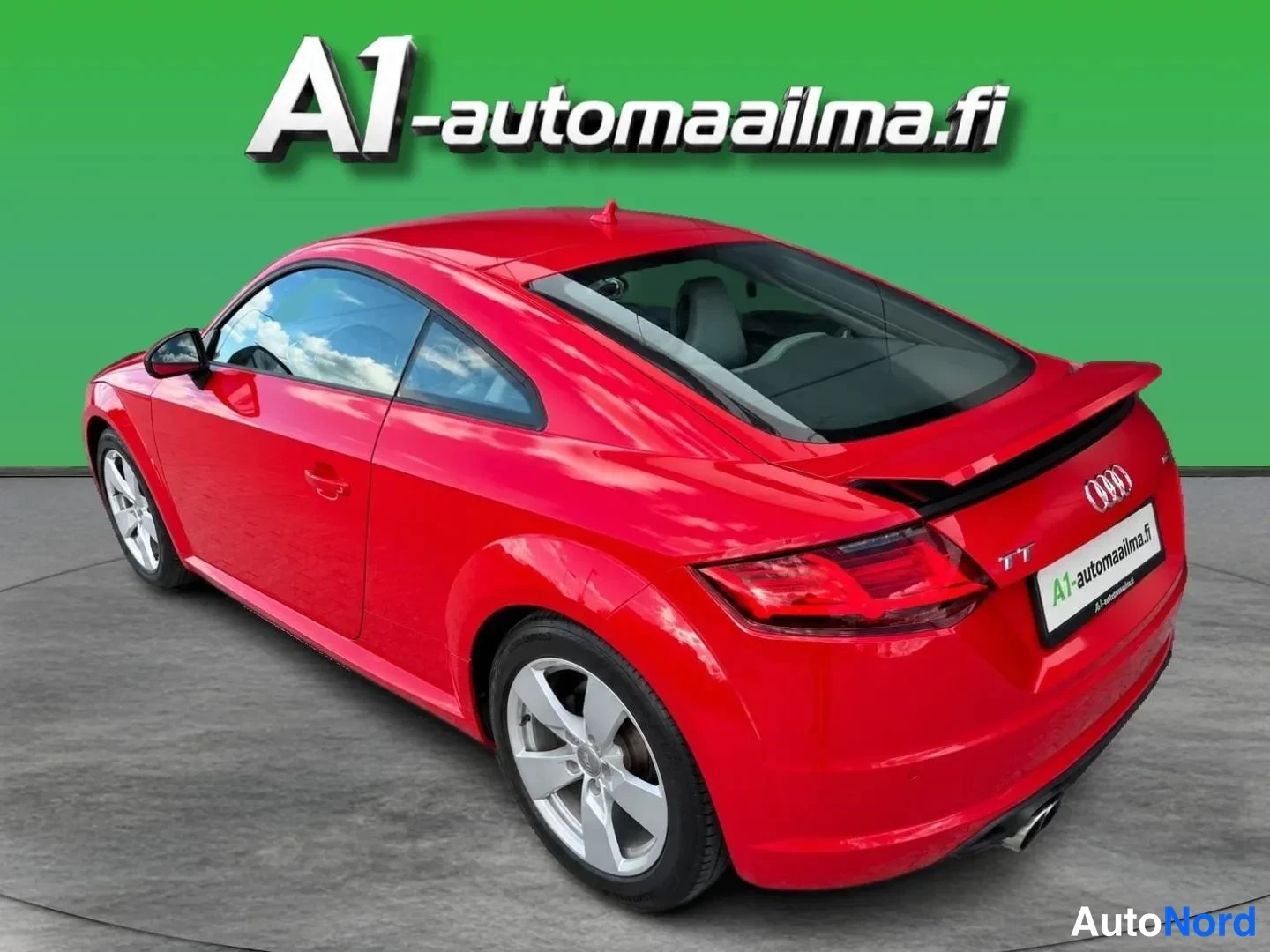 Takaviisto: Punainen Audi TT Coupé takakulmasta vasemmalta, takaspoileri ja perävaunu näkyvät.