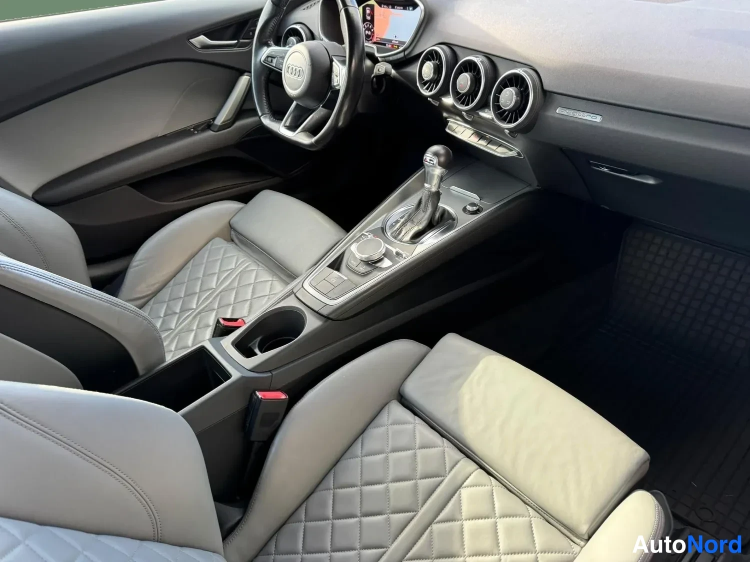 Sivulta: Audi TT:n sisätilat: hallinta- ja keskitunnustila, vaihdintausta ja harmaat punottujen istuinten etuinteet näkyvät matkustamon oikealta puolelta.